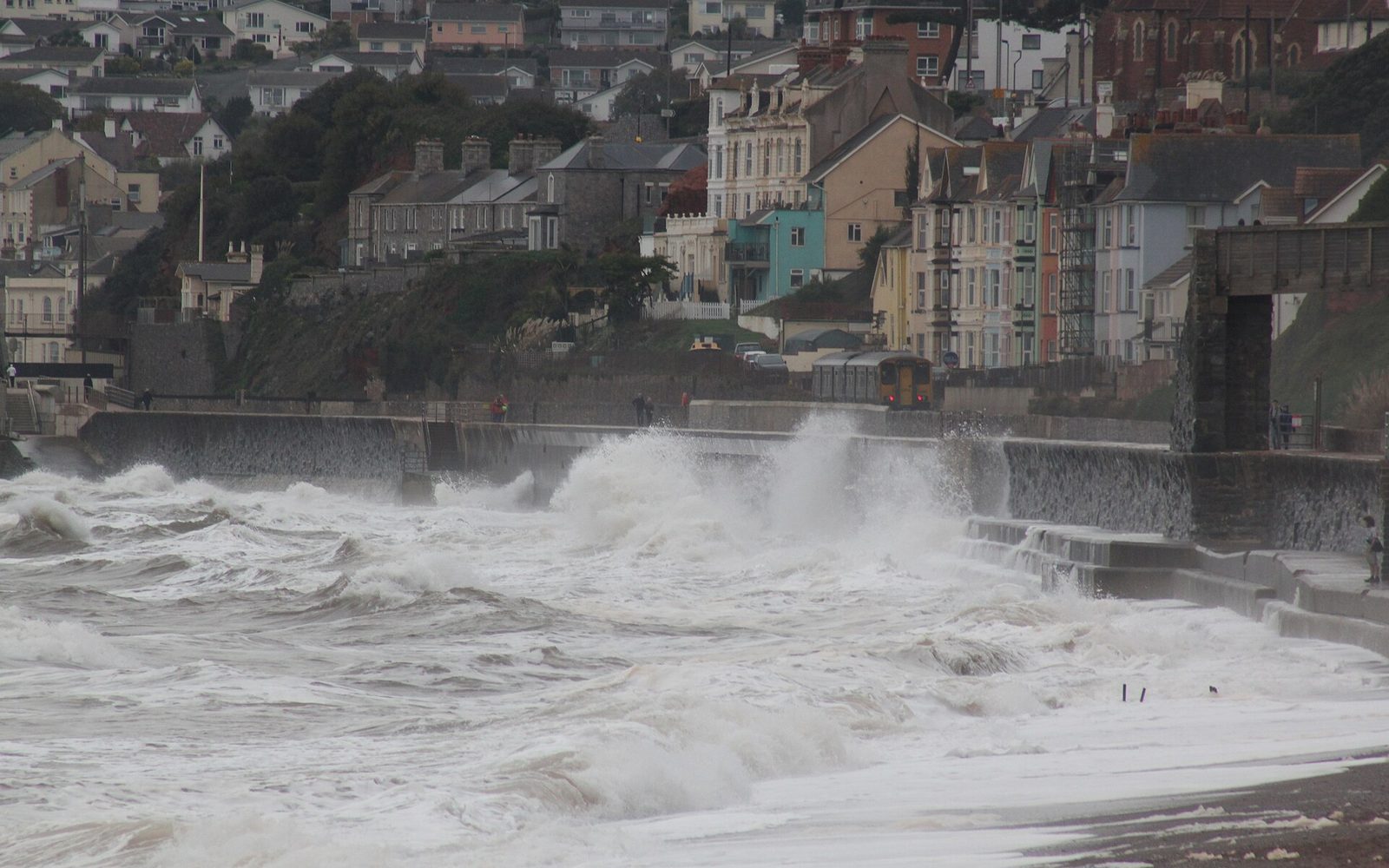 Storm waves breaking over the sea wall at Dawlish as a train passes